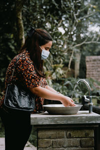 Side view of woman standing against plants