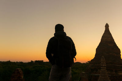 Man standing at temple against sky during sunset