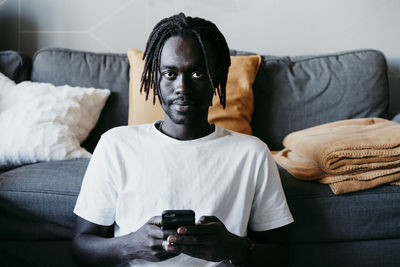 Portrait of young man sitting on sofa at home