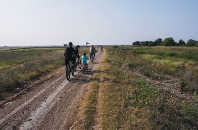 People riding bicycle on road against sky