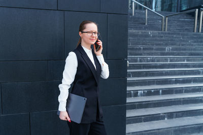 Happy woman in trendy glasses and business suit is focused on getting