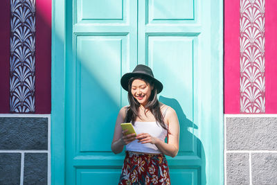 Full length of a young woman standing against wall