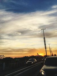 Cars on road against sky during sunset