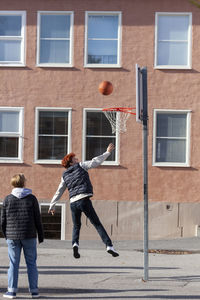 Teenage boys playing basketball in schoolyard