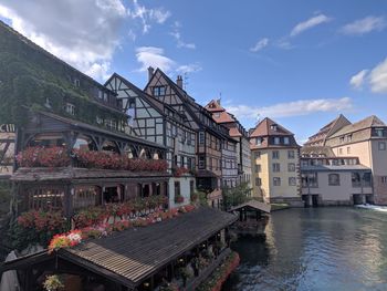 Buildings by river against sky in city