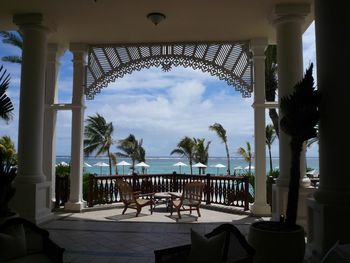 Chairs and table by swimming pool against sky seen from balcony