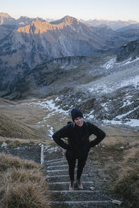 Full length of woman standing on steps against mountain range