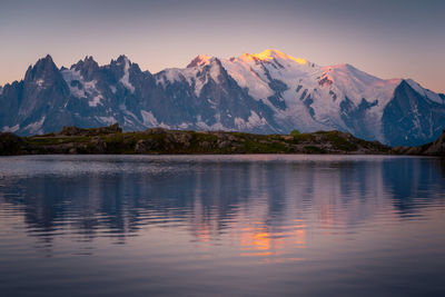 Scenic view of lake and mountains against sky during sunset