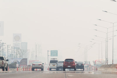 Traffic on road in city against clear sky