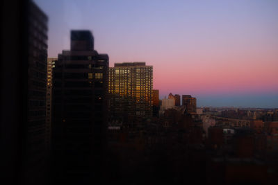 Buildings in city against clear sky at sunset