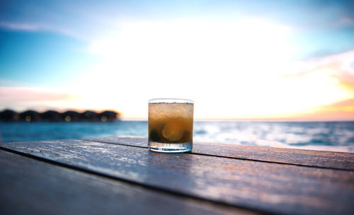 Close-up of glass of water on table against sky