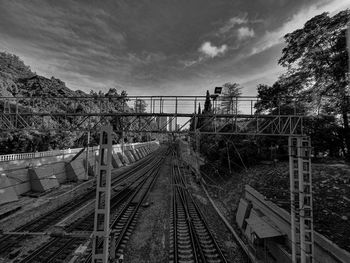 Railroad tracks by bridge against sky