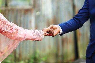 Midsection of couple holding hands while standing outdoors