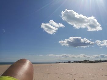 Low section of man on beach against blue sky