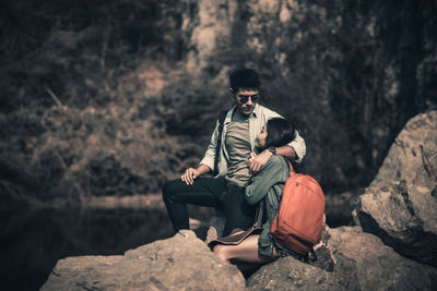 Man sitting on rock in forest