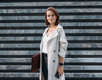 Portrait of young woman standing against wall