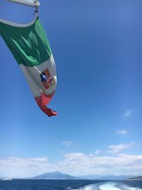 Low angle view of flags hanging against blue sky