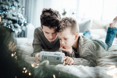 Cute boy playing with video game while lying on bed at home