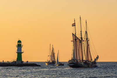 Lighthouse by sea against sky during sunset