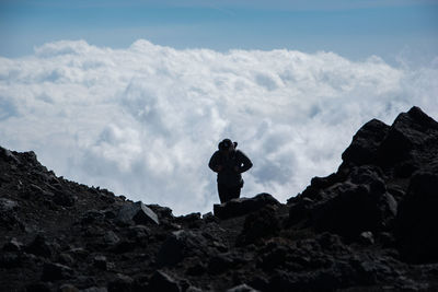 Man standing on rock against sky