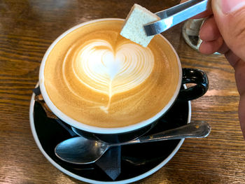 High angle view of coffee cup on table with sugar cube