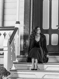 Full length of woman sitting on staircase against building