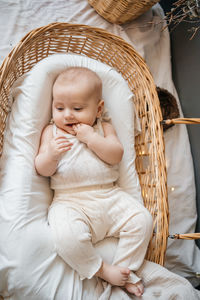 Baby lies in a wicker basket gray background willow eco style