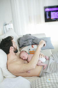 Midsection of baby lying on bed at home