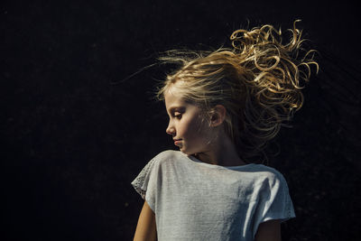 Girl looking away while standing against black background