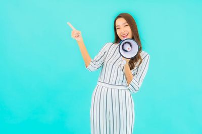 Woman photographing against blue background