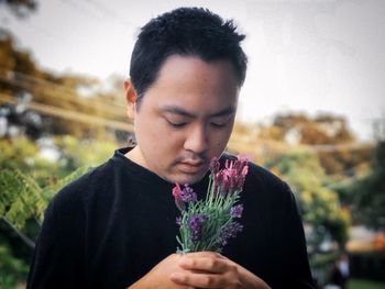 Portrait of young man holding purple flower