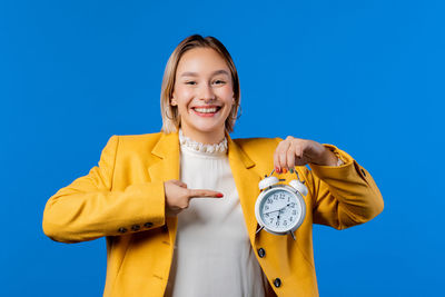 Portrait of young woman standing against blue background