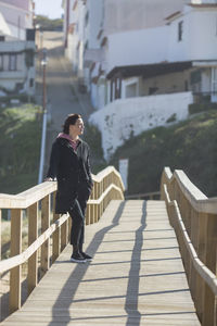 Woman standing on footbridge in city