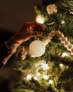 Cropped hand holding illuminated christmas tree