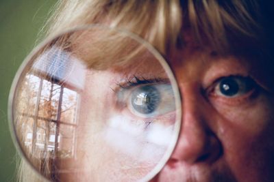 Close-up of woman looking through magnifying glass