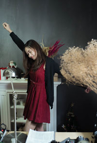 Beautiful young woman in red dress dancing at home