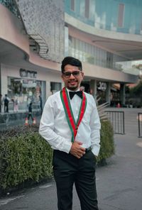 Portrait of young man standing against building in city