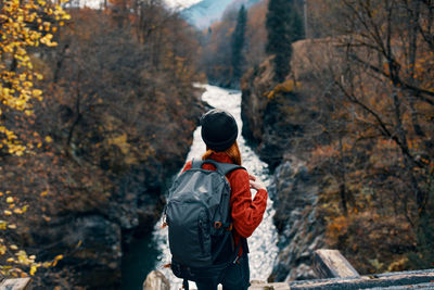 Rear view of man standing by trees during autumn