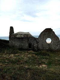 Castle by sea against cloudy sky