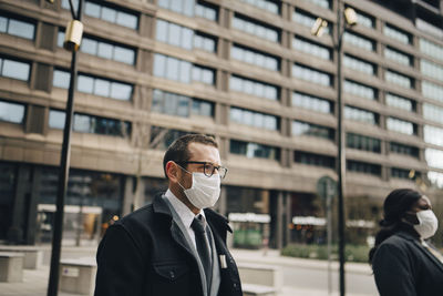 Mature business people in front of building during pandemic