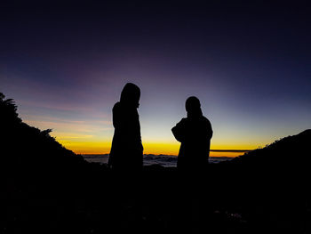 Silhouette people standing on land against sky during sunrise
