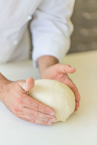 Midsection of man kneading dough on table