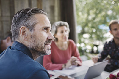 Businessman looking away while sitting at desk with colleagues in portable office truck