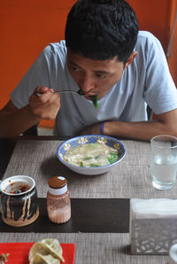 A asian guy eating thenthuk tibetan cousin in fast food cafe