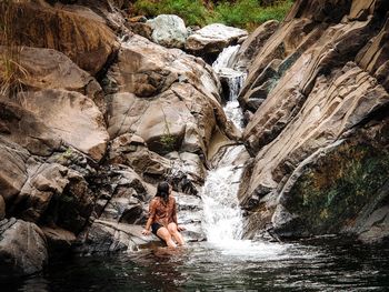 Man surfing on rock against waterfall