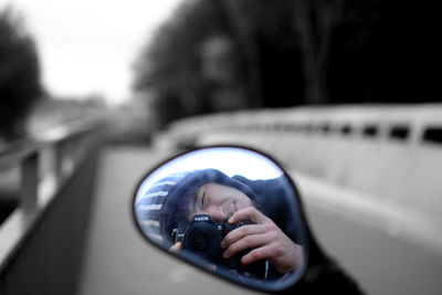 Reflection of man on side-view mirror
