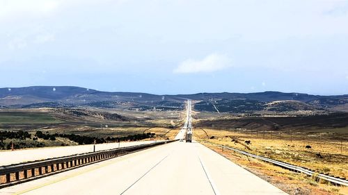 Empty road leading towards mountains against sky