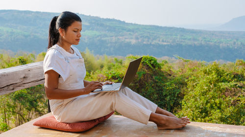 Portrait of young woman sitting on mountain