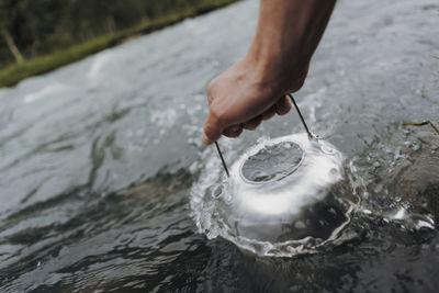 Cropped hand filling water in container at river