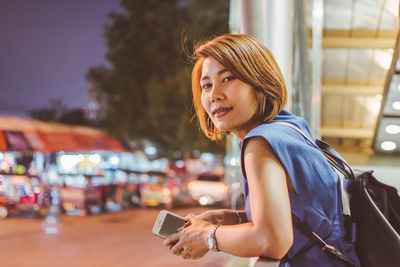 Portrait of woman standing in city at night